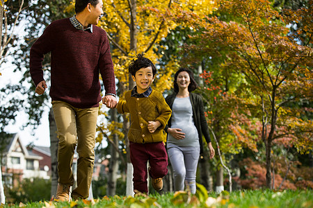 孕妇和小孩微笑男孩高兴的幸福家庭在户外玩耍背景