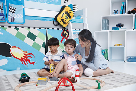 国际教育住宅内部蓝色装饰物可爱的小男孩和指导教师在游戏室玩耍背景