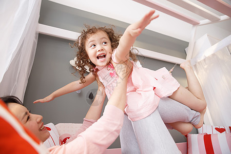 亲子游戏中年女人卷发彩色图片可爱的小女孩和妈妈在卧室玩耍背景