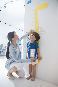 幼师家居尺青年女人在为小男孩测量身高图片