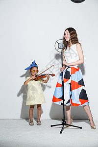 青年女人休闲装梦想小女孩和妈妈拉小提琴图片
