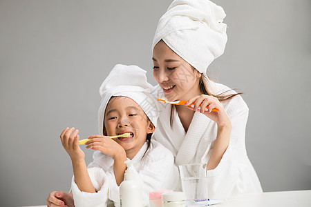 快乐亚洲女孩穿着浴袍的母女刷牙图片