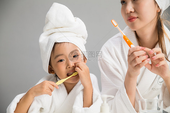 可爱的亲情愉悦穿着浴袍的母女刷牙图片