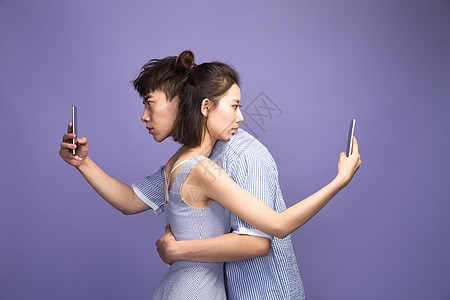 专心异恋休闲装各自玩手机的青年情侣图片