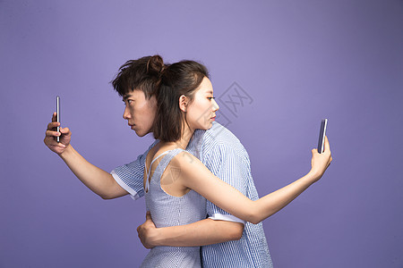 表现消极拥抱各自玩手机的青年情侣图片
