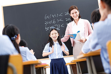 人群举手女教师和小学生们在教室里背景