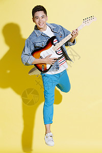 黄色背景酷动作青年男人弹吉他图片