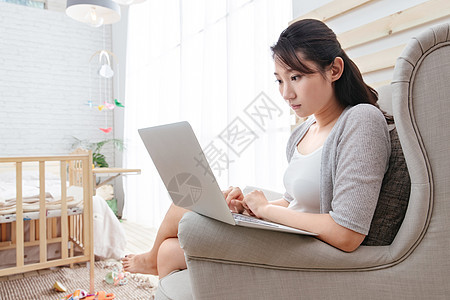 东方人20多岁愉悦青年女人坐在沙发上使用笔记本电脑图片