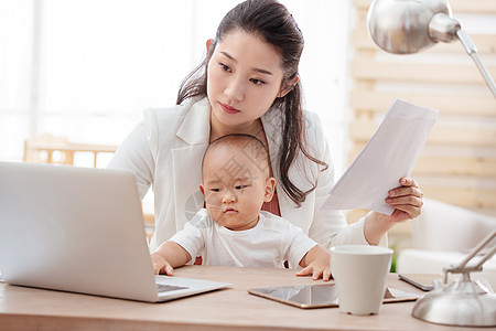 纸母子男婴年轻妈妈抱着孩子在家办公图片