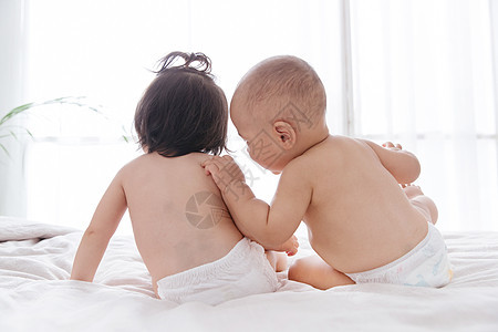 两个可爱宝宝坐在床上玩耍背景图片