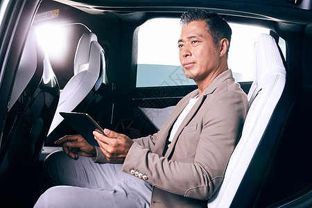轻松中年男人仅一个男人成熟男士坐在汽车里看平板电脑图片