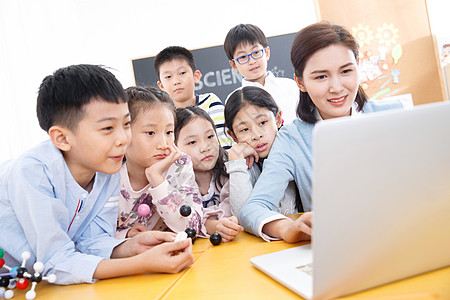 微笑的童年儿童女教师和小学生在教室里使用电脑高清图片