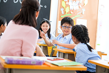 男孩和女孩女教师和小学生们在教室里背景