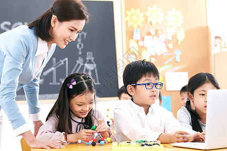 电脑学生女教师和小学生在教室里使用电脑背景