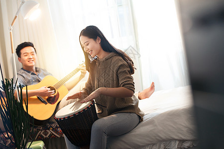 温馨白昼东亚快乐情侣在家演奏乐器图片