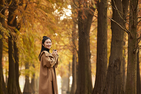 美女喝奶茶美女大学生手捧奶茶杯逛公园形象背景