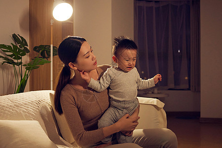 夜晚年轻宝妈安抚哭泣的宝宝图片