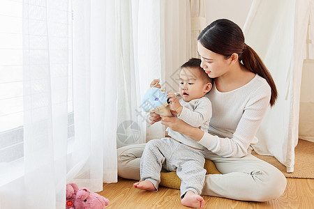 年轻妈妈陪孩子窗边玩耍背景