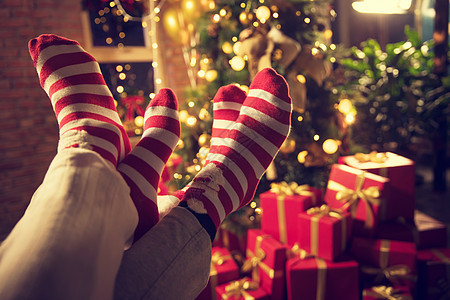 窗户圣诞礼物青年人穿着圣诞情侣袜的脚部特写图片