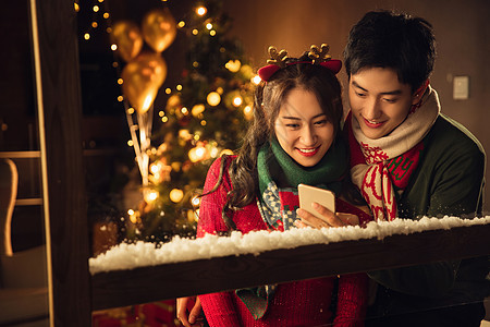 圣诞发卡男人快乐的年轻伴侣在家使用手机图片