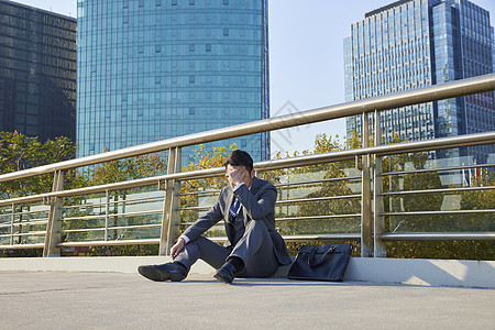 户外帐篷商务男士失落的坐在天桥上背景