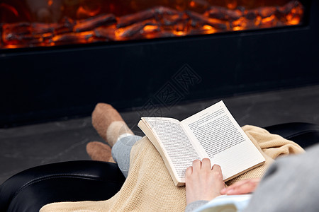 居家女性在暖炉前看书特写图片