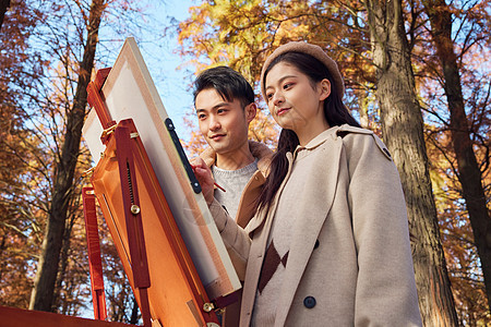 秋季户外情侣在公园里画油画背景图片