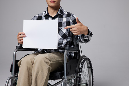 青年男性腿部受伤坐轮椅手指白板图片