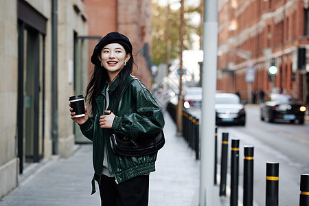 手拿咖啡行走街头的青年女性图片