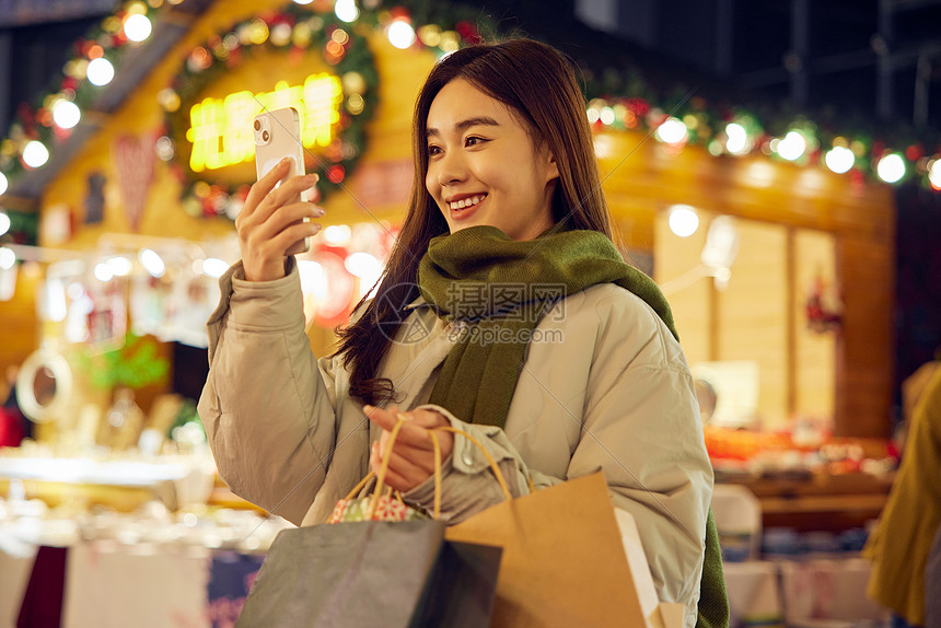 青年女性逛圣诞市集拿手机拍照图片