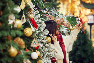 青年女性圣诞采购与圣诞树自拍图片