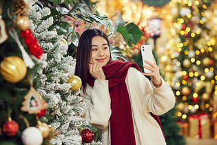 青年女性圣诞采购与圣诞树自拍图片