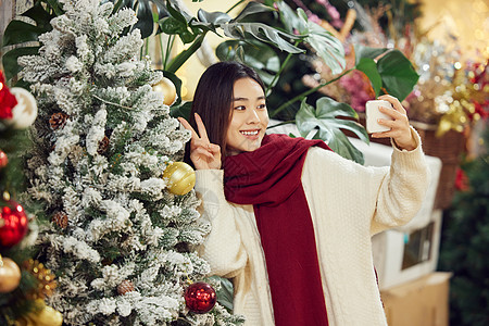 年轻女性手拿相机记录圣诞节日氛围图片