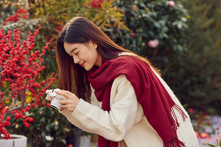 冬日女性花拿相机拍鲜花图片
