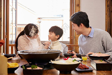 妈妈给吃火锅的儿子擦嘴背景图片