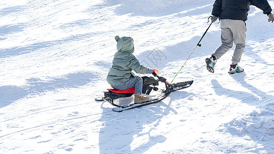 领着孩子的父亲雪地里父亲拉着孩子滑雪橇背景