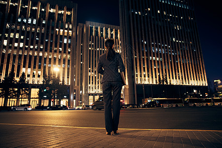 夜晚站在办公楼前的都市职场女性背影高清图片