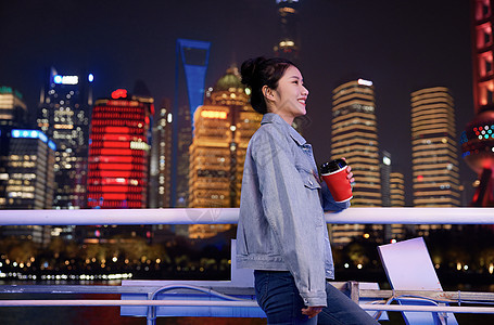 夜晚在游轮船上手捧咖啡的旅游女生图片