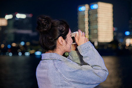 时尚青年夜晚正在使用相机拍照的女生背景