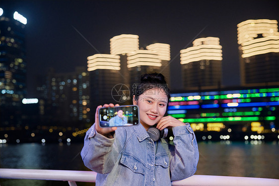 夜晚在游轮船上用手机自拍的旅游女生图片