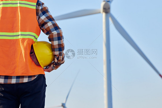 风车下男性工程师手拿安全帽特写图片