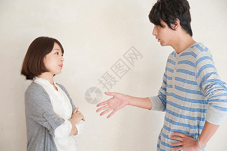 亚洲夫妻吵架：发怒的双人撅嘴，白墙见证愤怒图片