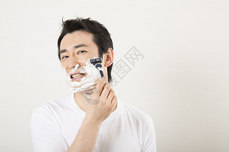 使用剃须刀刮胡子的男性图片
