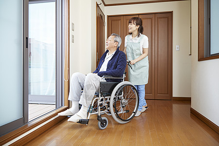 护工在室内推行坐在轮椅上的老人图片