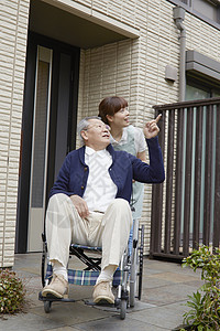 女性护工推着轮椅上的老人出门散步图片
