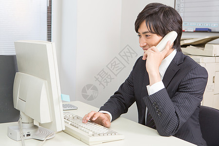 在工位上使用座机打电话的男性图片