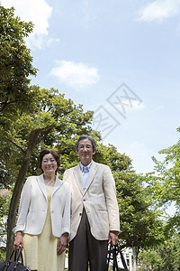 户外拎着行李包旅行的中年夫妇图片