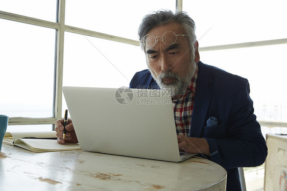 阅历丰富的中年男子在用笔记本工作图片