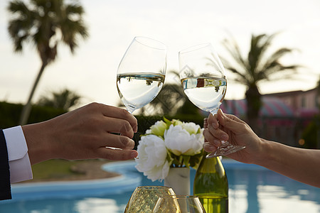 泳池边晚餐的情侣干杯特写图片