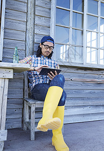 木屋外的男子手拿平板电脑背景图片